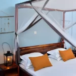 lit double à baldaquin moustiquaire, 2 tables de nuit avec lampes tempête et suspension coquillages