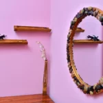 miroir décoré de petits galets, étagères en bois et mur rose